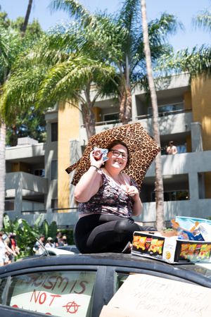 Los Angeles, CA, USA — June 14th, 2020: woman sits on top of car giving out free snacks at protest