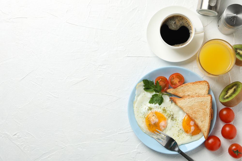 Top view of plate of fried eggs for breakfast on blue plate, copy space