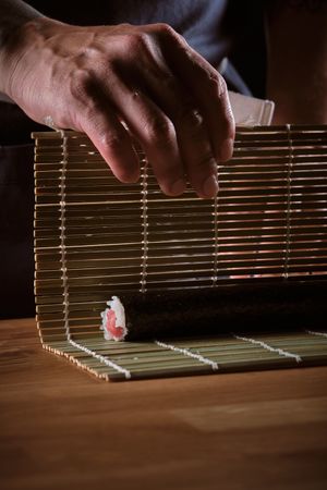 Male shushi man hands preparing different pieces of makis