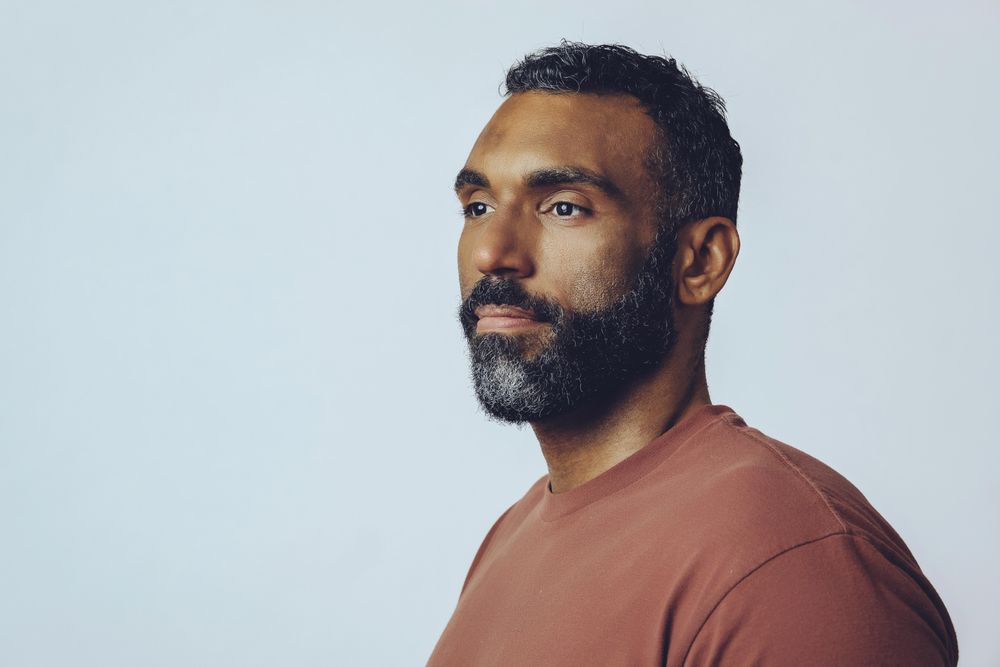 Portrait of calm Black male looking away in grey studio