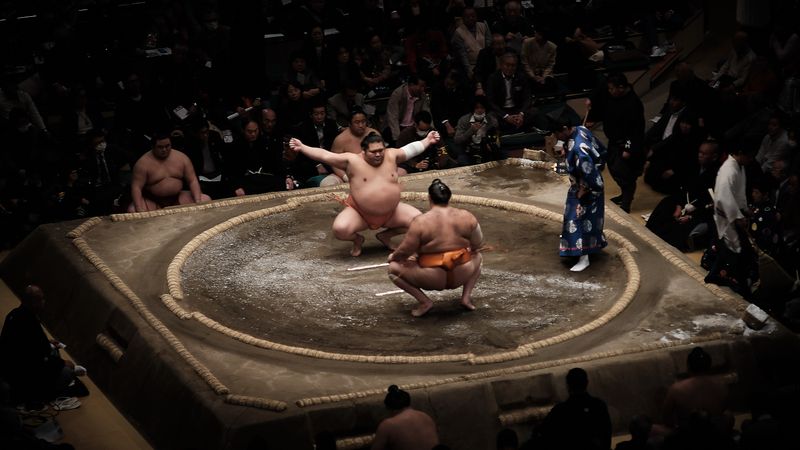 Two sumo fighter crouching in the arena
