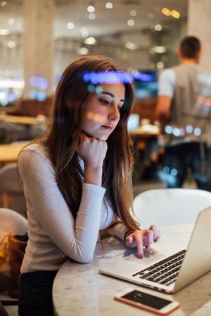 Brunette woman in a restaurant working on her laptop