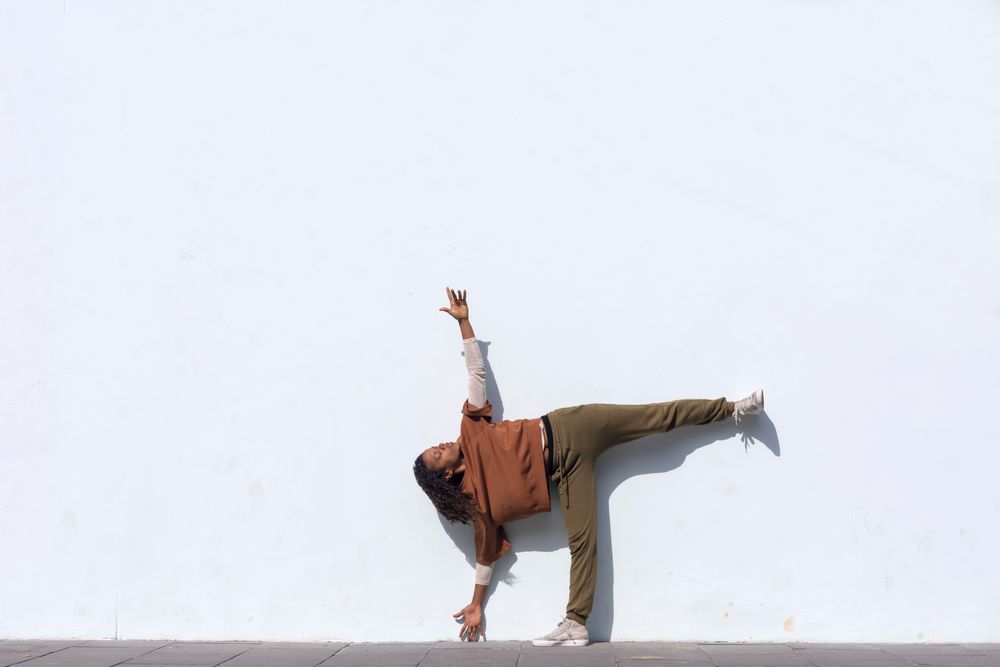 Woman in sporty clothes stretching before running against wall