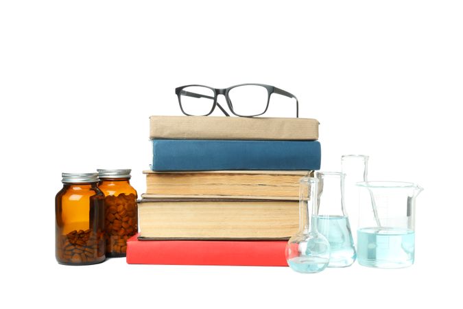 Books, flasks, glasses and jars of pills, isolated on light background