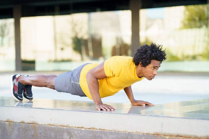 Side view of man doing planks on cement outside