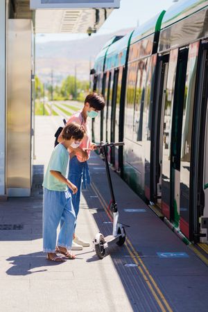 Mother and daughter boarding a tram with scooter
