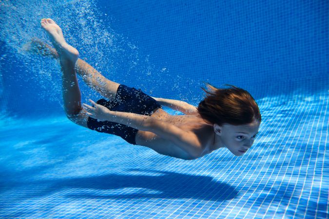 Kid in swimsuit diving into pool