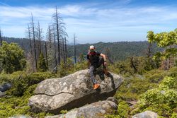 Relaxed hiker resting on big rock in forest