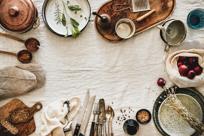 Vintage kitchen utensils and knifes artfully arranged on beige tablecloth, with copy space