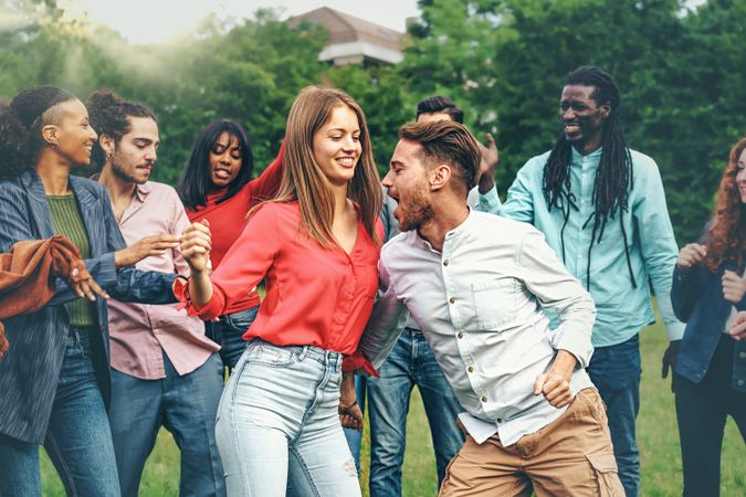 Multi-ethnic group of young men and women dancing in nature