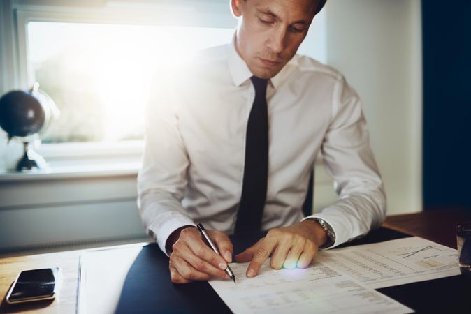 Man in shirt and tie with pen in sunny office