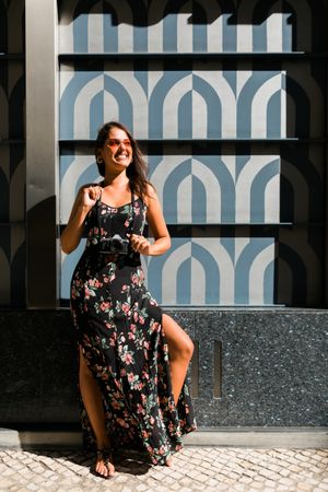 Dreamy stylish woman in sunglasses standing on city street