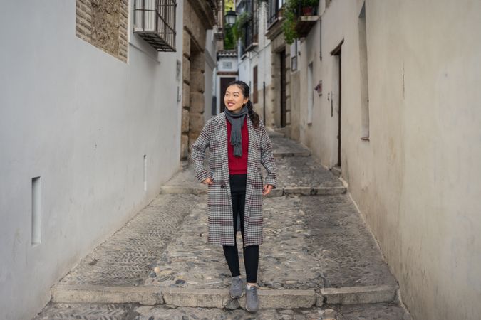 Joyful female tourist in casual wear amid city street