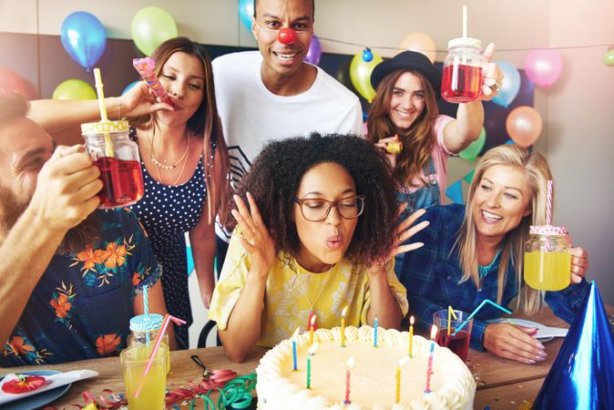Black woman surrounded by friends as she blows out birthday candles
