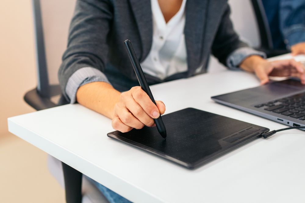 Close-up of an unrecognizable woman using a graphics tablet in an office