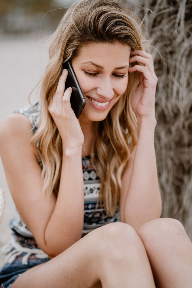female talking on smartphone on beach