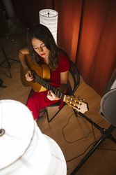 Woman singing and playing guitar on stage in lamplight