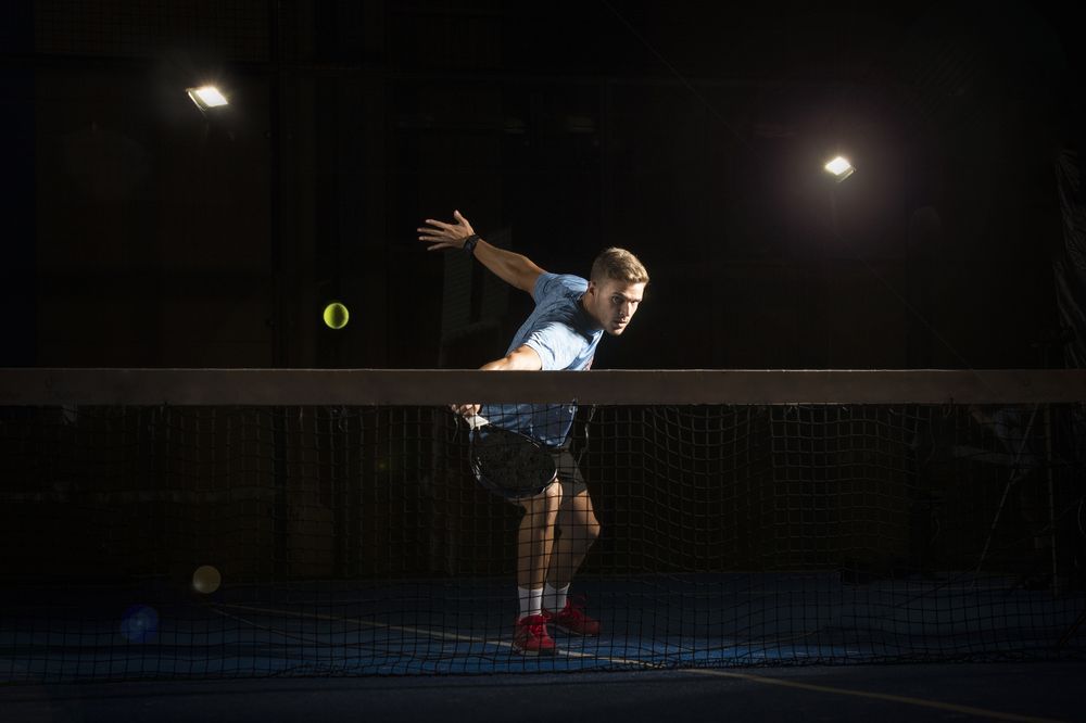 Man playing padel in darkness
