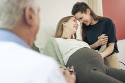 Loving lesbian couple sharing an intimate moment during a pregnancy check-up.
