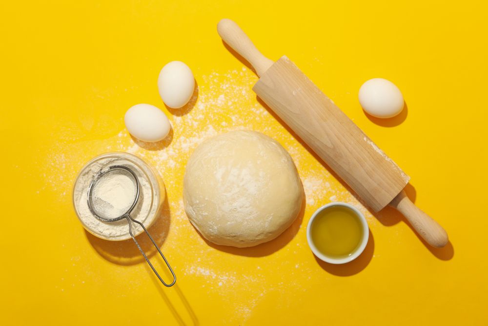 Concept for baking with dough on yellow background