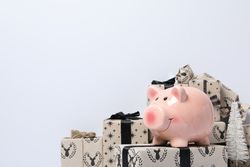Piggy bank on gift boxes on light background, space for text