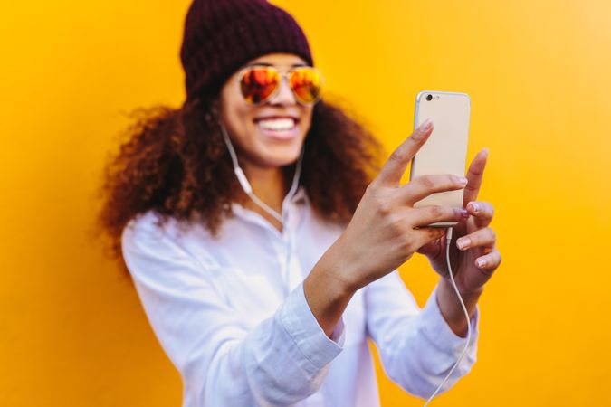 Happy woman wearing earphones and watching something on her smart phone