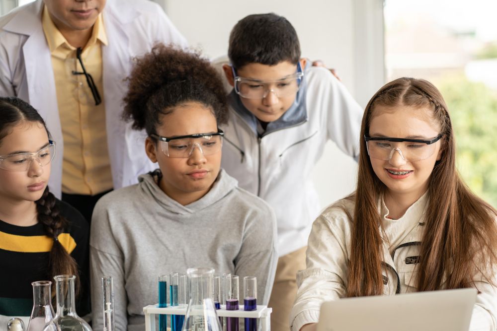 Enthusiastic multi-ethnic students in protective eye wear with teacher