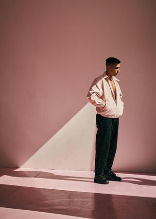 Young man in contemplative pose in blank room with light shining through