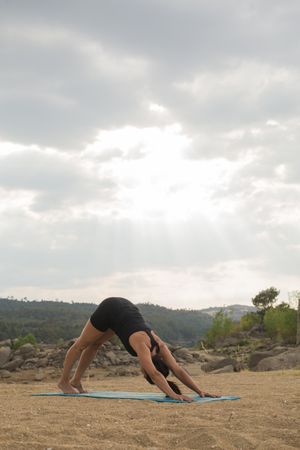 Woman practicing yoga outdoors near water