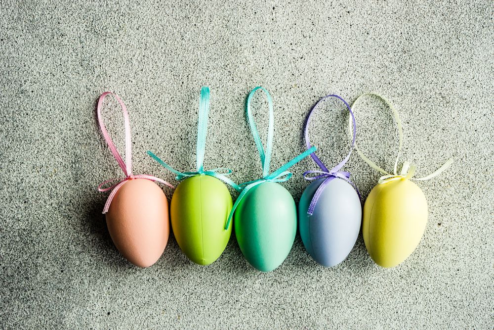 Easter card concept with line of pastel egg ornaments on concrete table