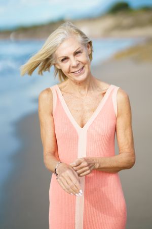 Mature woman walking happily along coast