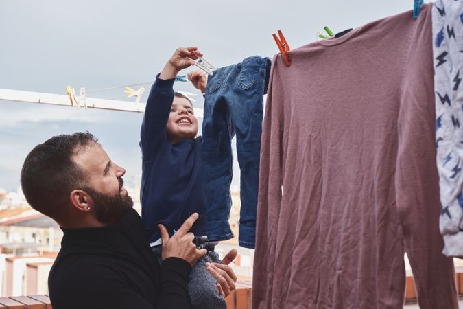 Father and son hanging clothes on rope