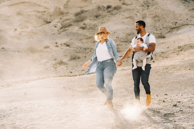 Diverse parents dancing while walking with baby