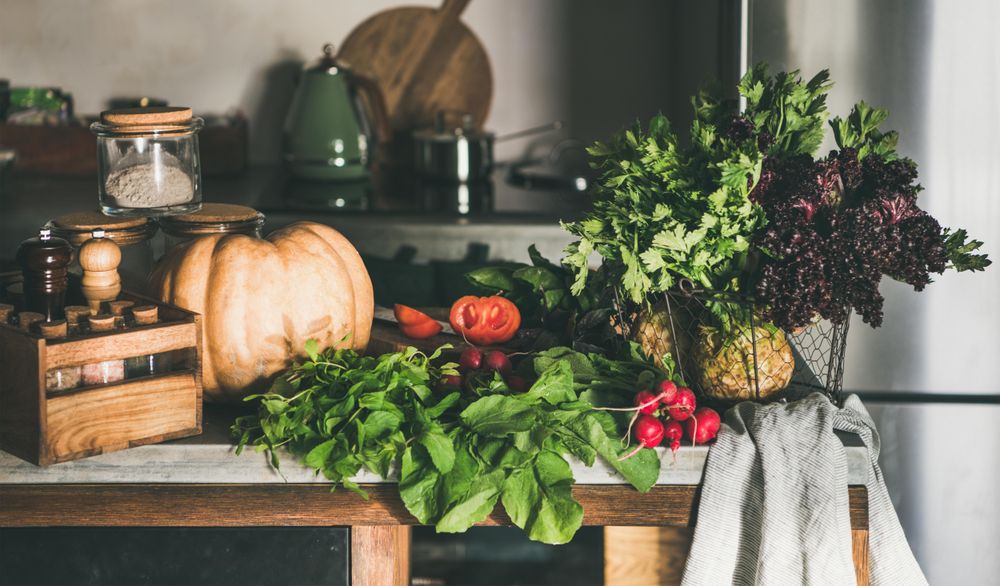 Assortment of vegetables, squash, tomatoes, radishes, herbs, on rustic kitchen counter