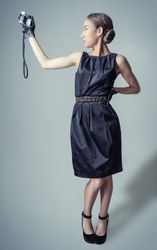 Model in vintage clothing and gloves taking selfie with camera