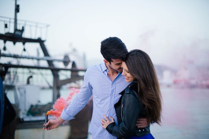 Young man holding smoke bomb and hugging woman being in love