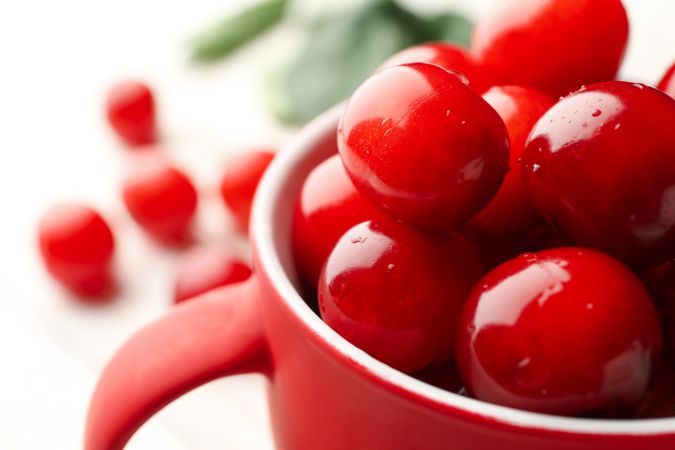 Cup with fresh red cherry on plain background, close up