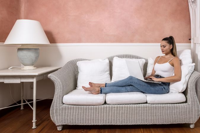 Woman using laptop sitting on light couch