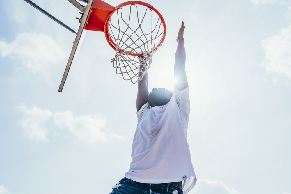 Black sportsman hanging on basketball lap