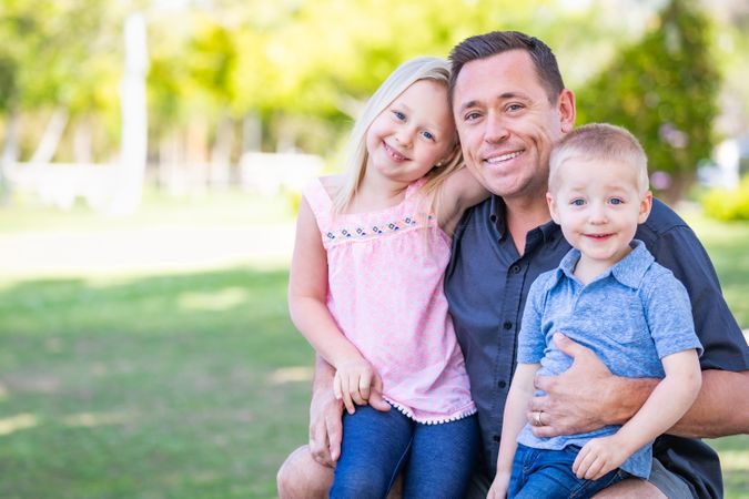 Young Dad, Son and Daughter Having Fun In The Park