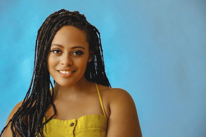 Portrait of happy female with long braided hair in yellow clothes, copy space