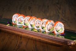 Sushi rolls on serving plank with reflective surface