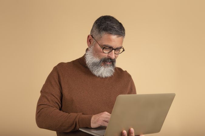 Bearded man in brown sweater using computer