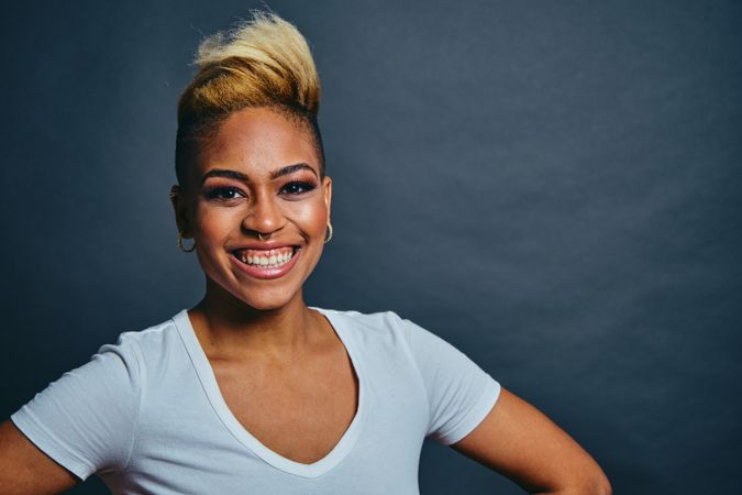Joyful Black woman with short blonde hair with hands on her hips