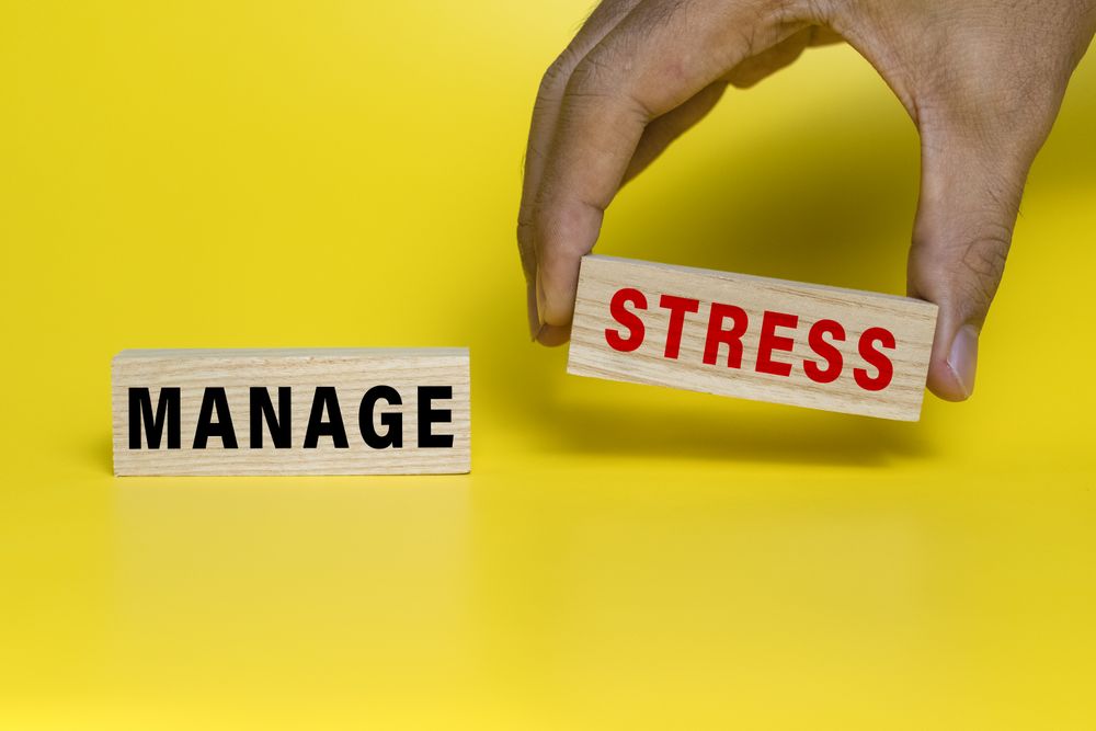male hand put manage stress words text on wooden blocks isolated on yellow background