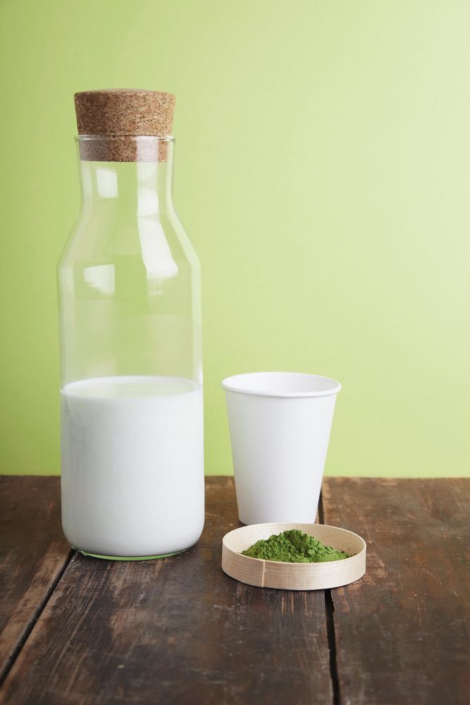 Ingredients for a matcha latte on green background