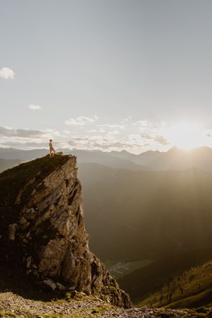Person standing on rock formation looking at mountains