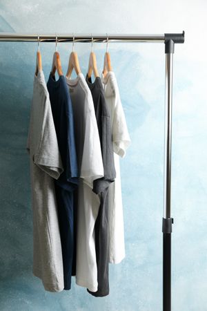 Rack with blank t-shirts on blue background.