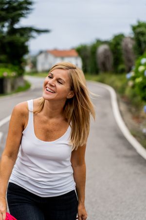 Joyful woman walking on marked road looking away