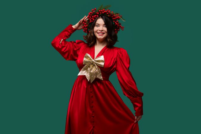 Happy woman in red dress with berry wreath